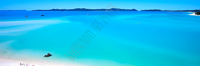A panoramic aerial view of Whitehaven Beach's turquoise water and white sand, with a small boat and beachgoers below.
