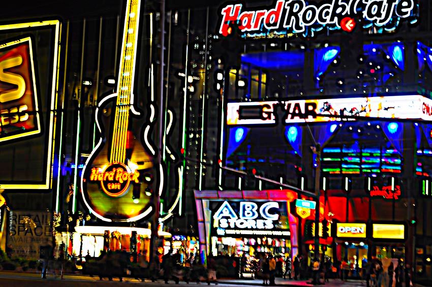 Neon signage, including a guitar and the Hard Rock Cafe logo, on the Las Vegas Strip at night.