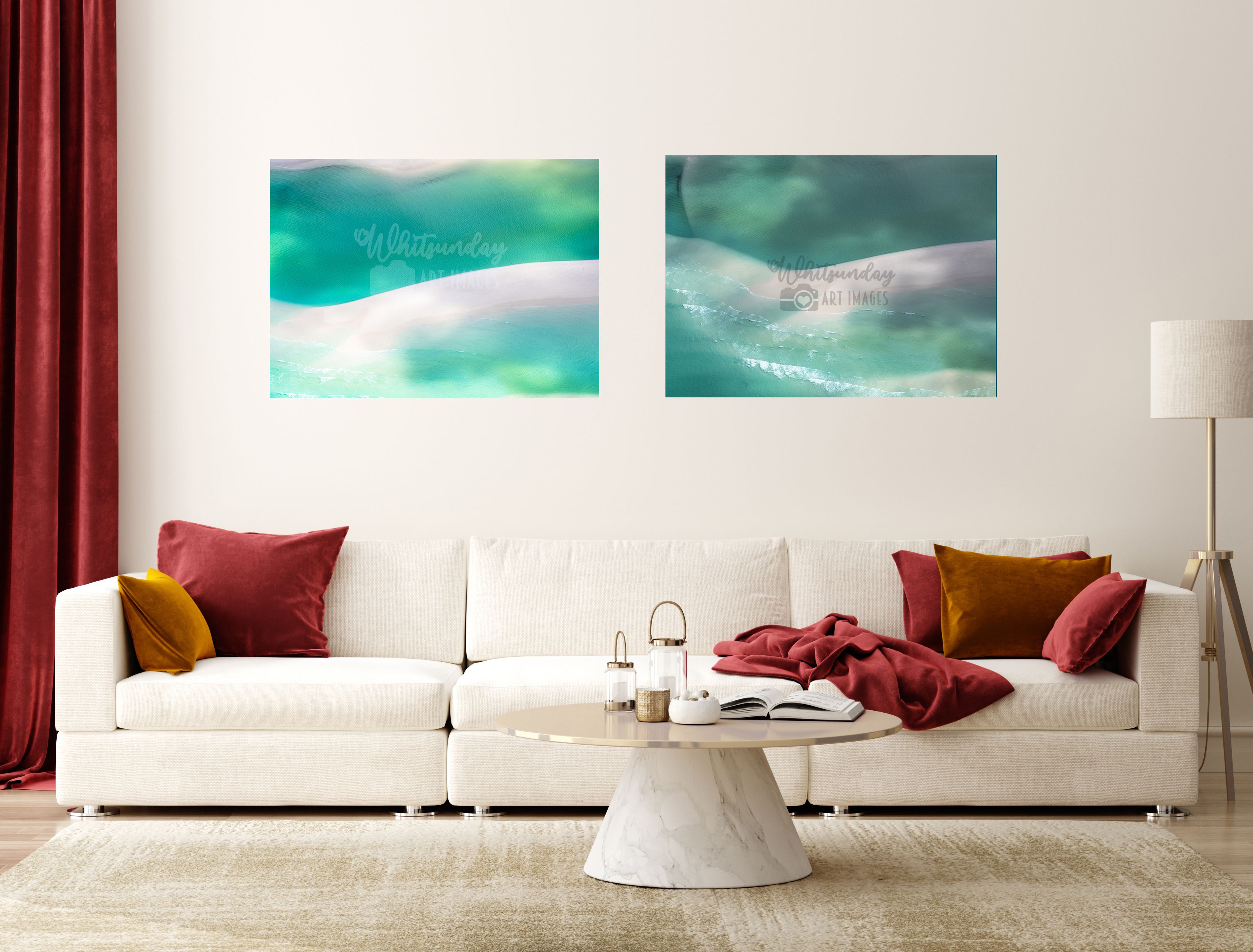Two abstract turquoise-and-white reef-edge photographs displayed side by side above a cream sofa with red and gold cushions.