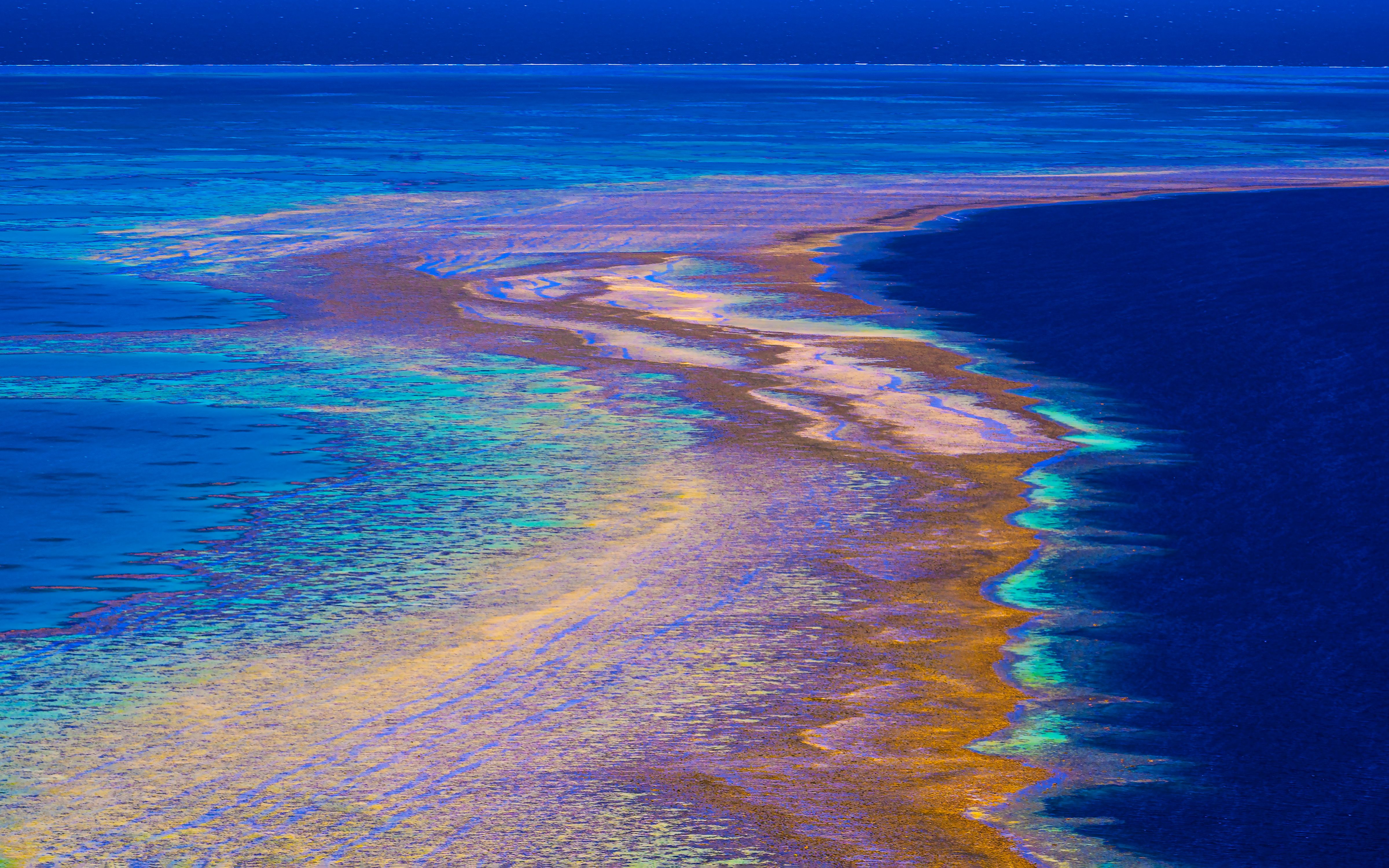 Aerial view of golden reef flats giving way to deep blue ocean in a warm, stylised palette.