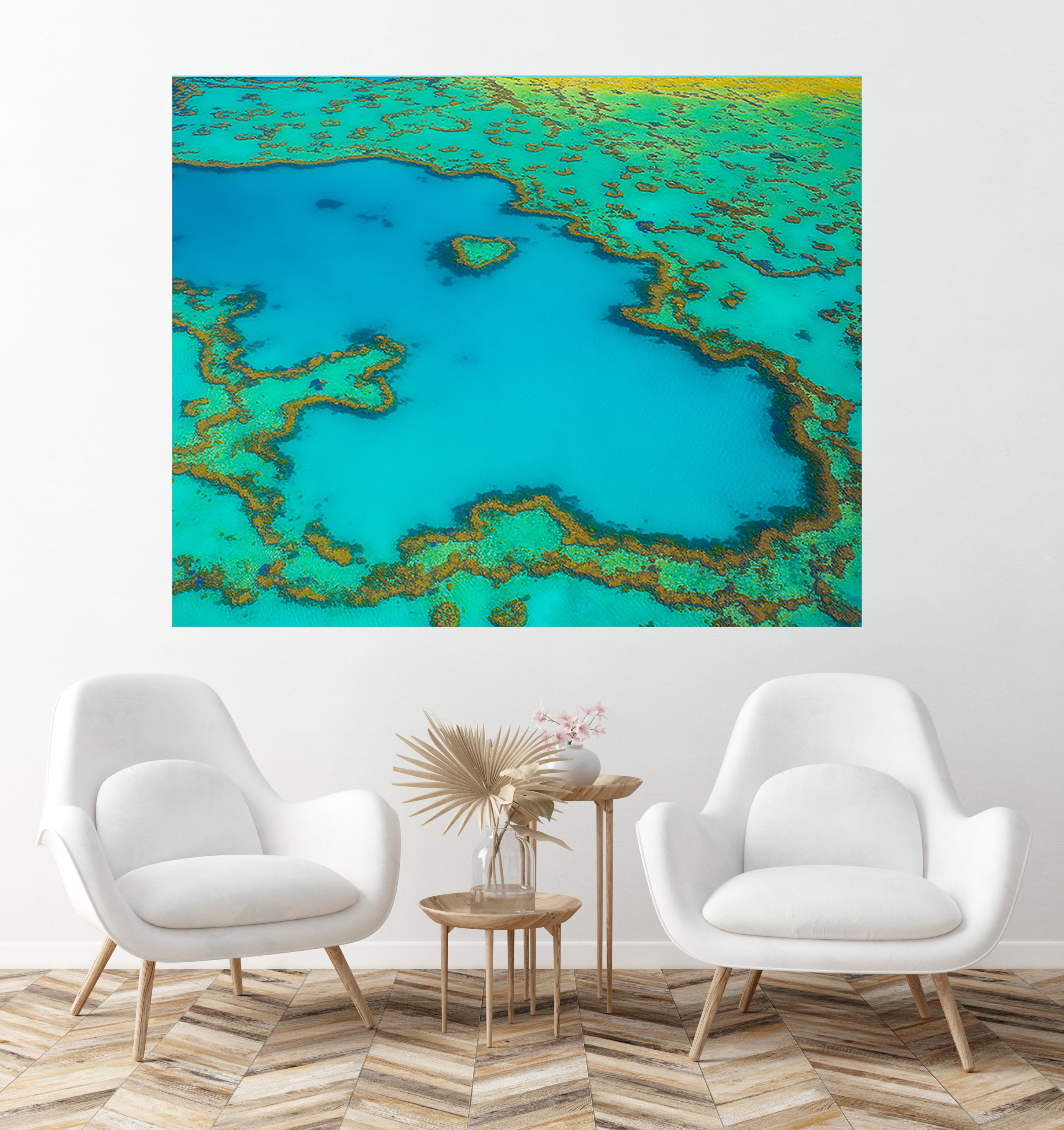 A large aerial reef photo, including a heart-shaped coral formation, shown as a metal print above white armchairs.